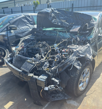 Severely damaged car with crushed front end and exposed engine components after a serious crash caused by fatigued driving.